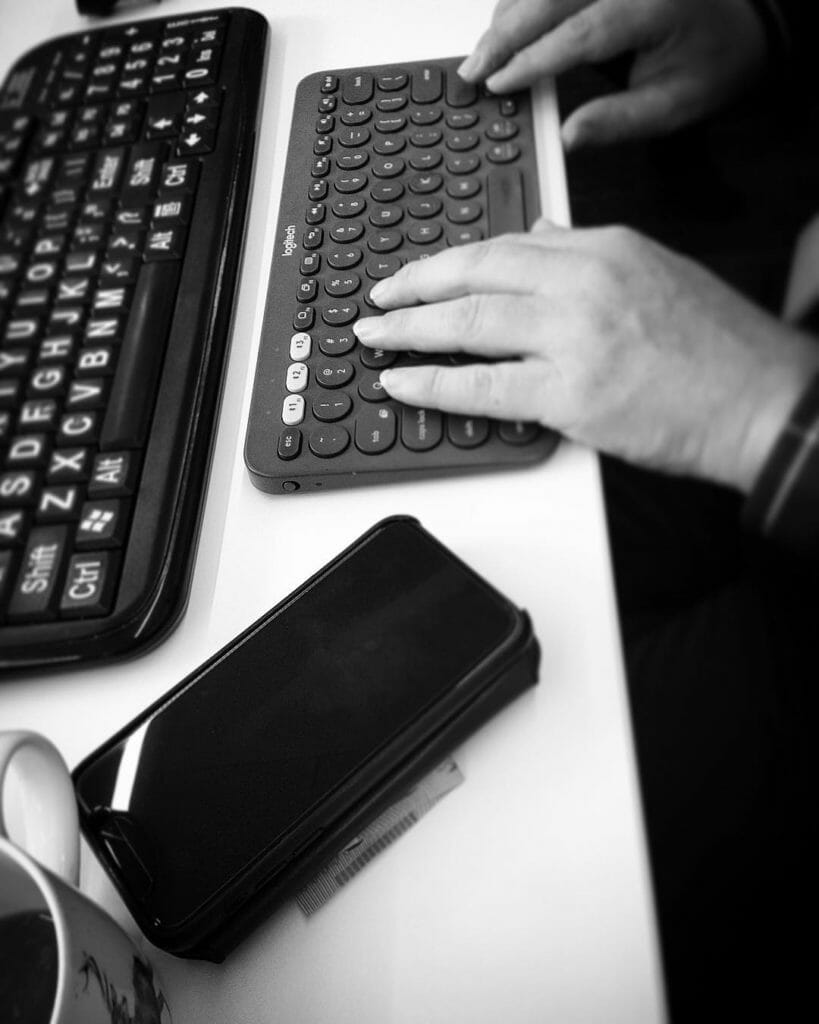 Our participant has their hands operating their bluetooth keyboard and iPhone to fill in a form during a usability test session.